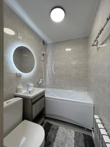 ein Badezimmer mit einer weißen Badewanne, einem WC und einem Waschbecken in der Unterkunft Люкс 1-комнатная квартира in Balqasch