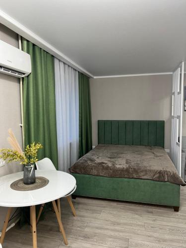 ein Schlafzimmer mit einem grünen Bett und einem Tisch in der Unterkunft Люкс 1-комнатная квартира in Balqasch
