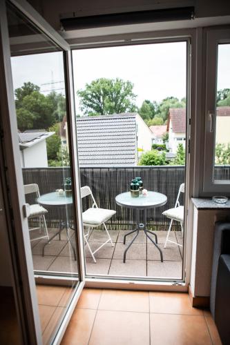 a patio with two tables and chairs on a balcony at Art & Nature Apartments in der Nähe FFM-Messe in Bad Vilbel