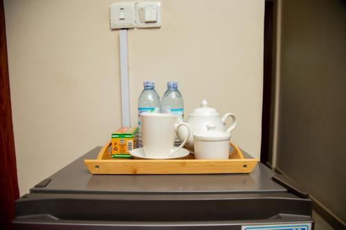 Una bandeja con botellas y tazas encima de un refrigerador. en Edge Studio Apartment, en Kampala