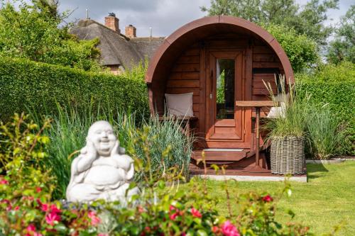 Un jardín con una estatua delante de una pequeña cabaña. en Sylter Seestern Haus Matzen Hüs, en Morsum