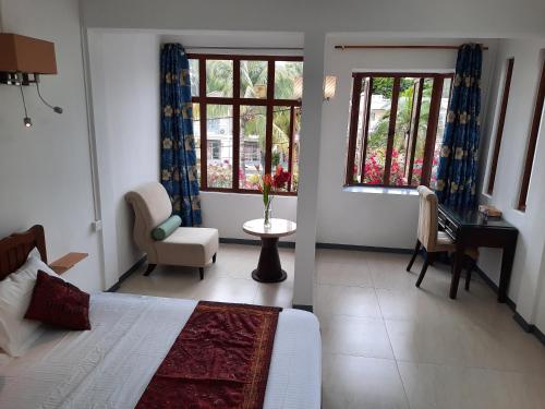 a bedroom with a bed and a table and two windows at Jasmin Apartments flic en flac in Flic-en-Flac