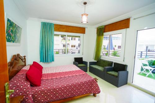 a bedroom with a bed and a couch and windows at Bright Apartment with Sea View, few steps away from the TGV in Tangier