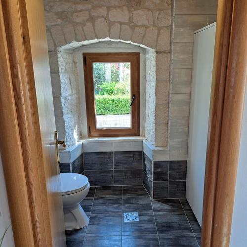 a bathroom with a toilet and a window at apartman "Dora" in Rogoznica