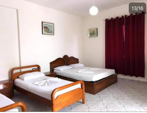 due letti in una stanza con tende rosse di Vila Victor a Vlorë