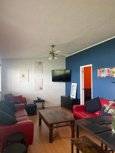 a living room with couches and a tv on the wall at Driftwood & Daisies- Red Buoy Retreat in Hemsby