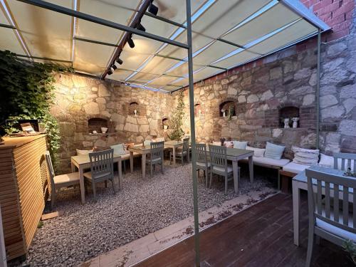 a patio with tables and chairs and a stone wall at Hanole Guest House in Ayvalık