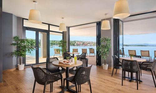 a restaurant with tables and chairs and a view of the water at Aminess Style Glamping Villas & Holiday Homes Atea in Njivice