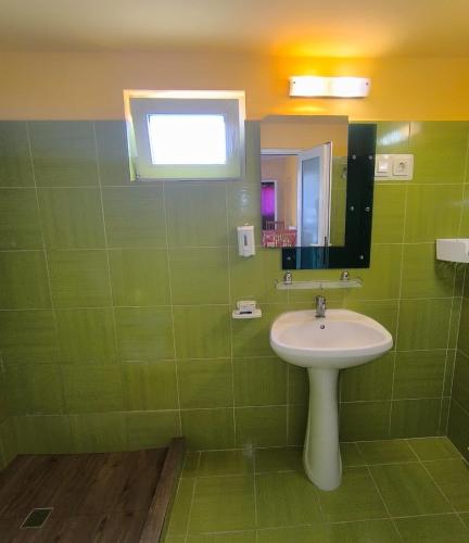 a green bathroom with a sink and a mirror at Casa de vacanță Anni - 2 min de piață in Eforie Nord