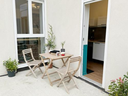 une table et des chaises en bois sur une terrasse dans l'établissement Nostalgie 90- emplacement idéal- parking gratuit, à Boulogne-sur-Mer