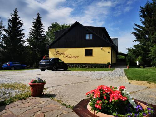a yellow house with a black roof and some flowers at Penzion Kovářov in Frymburk