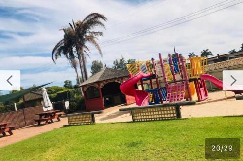 a playground with a colorful slide in a park at Black swan motor inn in Lakes Entrance