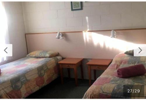 a hotel room with two beds and two tables at Black swan motor inn in Lakes Entrance