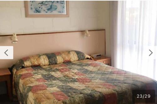 a bedroom with a bed with a quilt on it at Black swan motor inn in Lakes Entrance