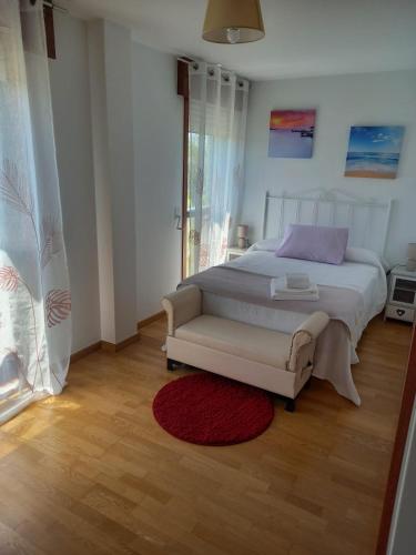 a bedroom with a white bed and a red rug at Piso DJC in O Pedrouzo
