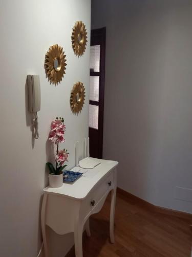 a white table with flowers and mirrors on a wall at Piso DJC in O Pedrouzo