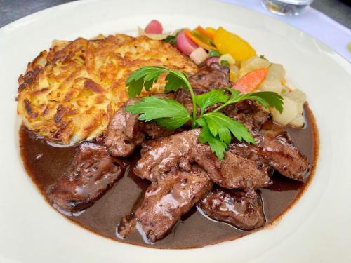 a plate of food with meat and vegetables on a table at Hotel Restaurant Croix Blanche in Sugiez