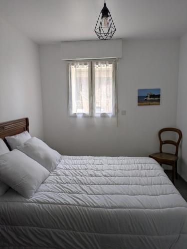 une chambre avec un lit blanc avec une fenêtre dans l'établissement Maison de famille Meschers sur Gironde à 14 mn à pieds de la plage, à Meschers-sur-Gironde