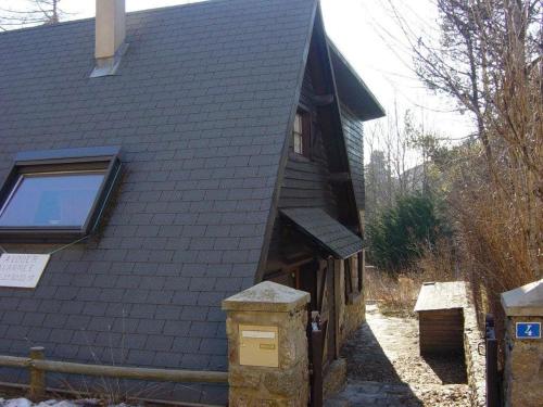 ein Haus mit einem Gebäude mit einem Zaun daneben in der Unterkunft Chalet in Bolquere
