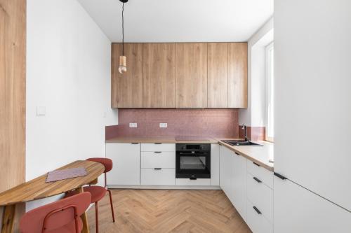 Una cocina con gabinetes blancos y una mesa de madera. en Studio w sercu Gdyni, en Gdynia