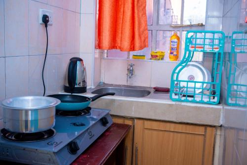 a kitchen with a stove with a pot on it at Gany Home Vibes - Comfy 1-bedroom apartment in Nairobi with Parking and Netflix - TRM drive in Nairobi