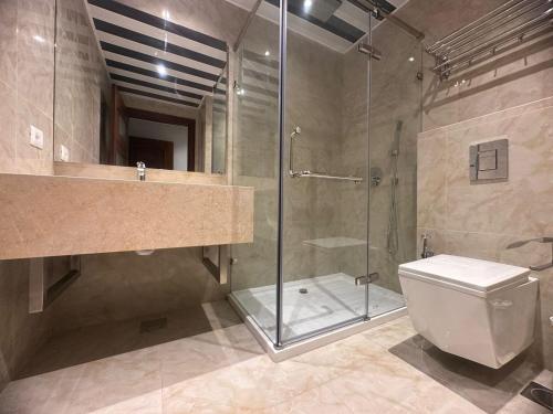 a bathroom with a glass shower and a toilet at 365 UrbanLiving in Jbeil