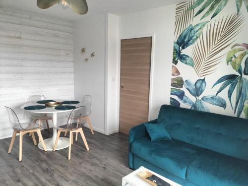 un salon avec un canapé bleu et une table dans l'établissement Appartement vue mer, à Les Sables-dʼOlonne
