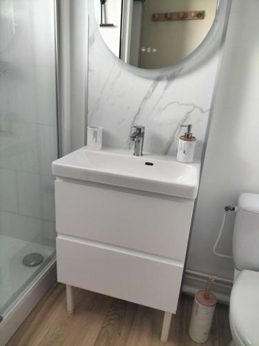 une salle de bain blanche avec un lavabo et un miroir dans l'établissement Appartement vue mer, à Les Sables-dʼOlonne
