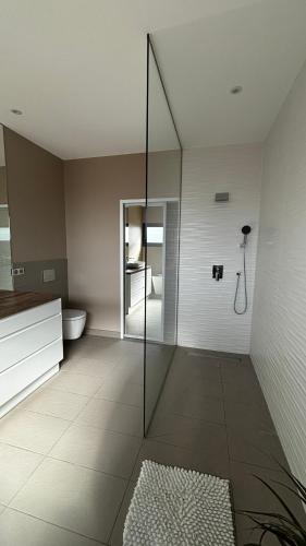une salle de bain avec une douche en verre et des toilettes dans l'établissement Maison moderne proche plages, à Saleilles