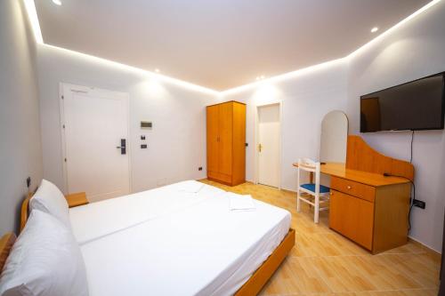 a bedroom with a bed and a desk and a television at Hotel Sea Breeze in Sarandë