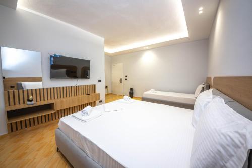 a hotel room with two beds and a flat screen tv at Hotel Sea Breeze in Sarandë