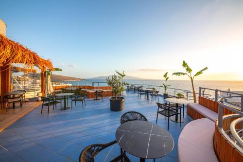 a patio with tables and chairs and the ocean at Hotel Sea Breeze in Sarandë