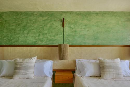 two beds in a room with a painting on the wall at Punta Nayaá - Adults Only in Puerto Escondido