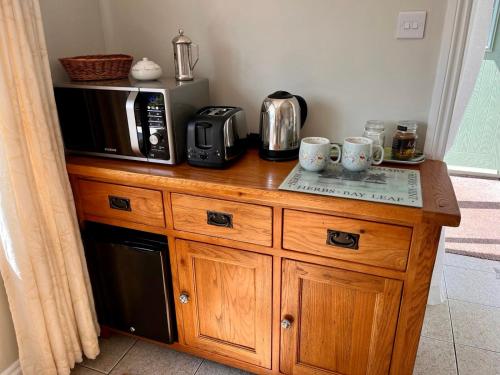 un comptoir en bois avec un micro-ondes et des tasses à café dessus dans l'établissement Sunnyside Guest Suite, à Kerne Bridge