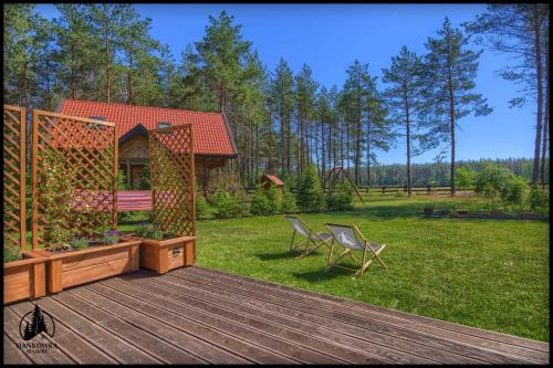 a wooden deck with a chair and a house at Hankówka Mazury in Jerutki