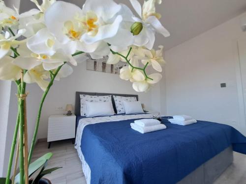 Un dormitorio con una cama azul con flores blancas en la pared. en Villa Mare Pirovac, en Pirovac