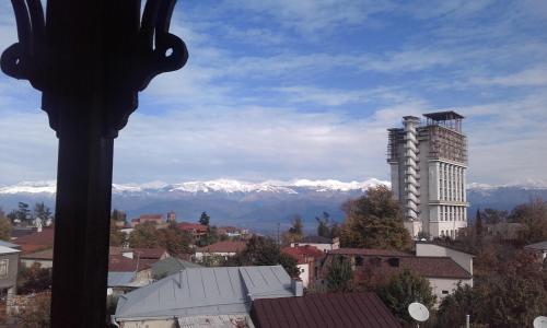 a city with a building and mountains in the background at Guest House Top Floor in Tʼelavi