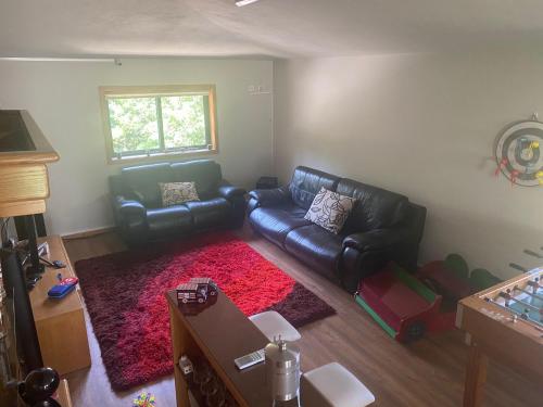 ein Wohnzimmer mit einem schwarzen Ledersofa und einem roten Teppich in der Unterkunft A Quinta do Presidente 