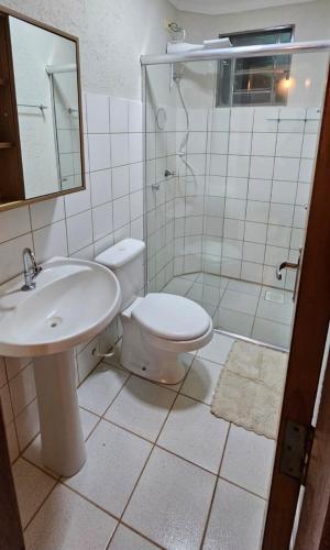 a bathroom with a toilet and a sink and a shower at JM03 Apartamento com Ar Condicionado e Garagem in Dourados