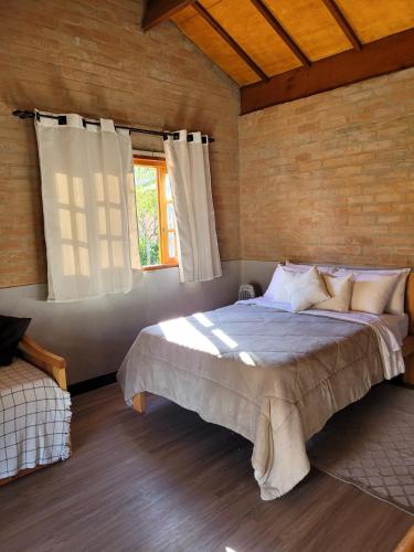 a bedroom with a large bed and a window at Chalé Rústico Moderno no Cantagalo in São Bento do Sapucaí