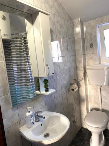 a bathroom with a sink and a toilet and a mirror at Apartments Stegic in Tivat
