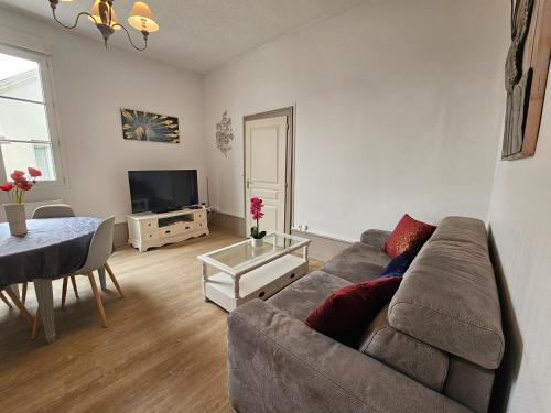 a living room with a couch and a table at T2 Ctre ville Fibre Literie Emma in Montrichard