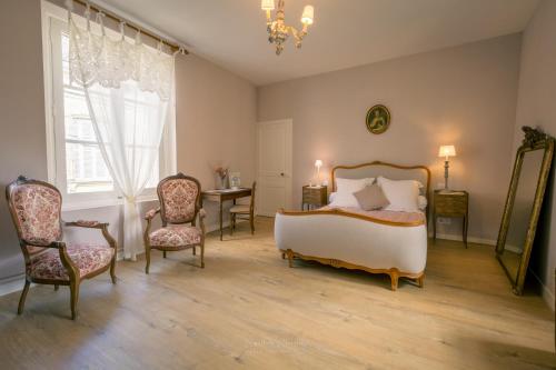 une chambre avec un lit, deux chaises et une table dans l'établissement Le Prieuré Sainte Croix, à Loudun