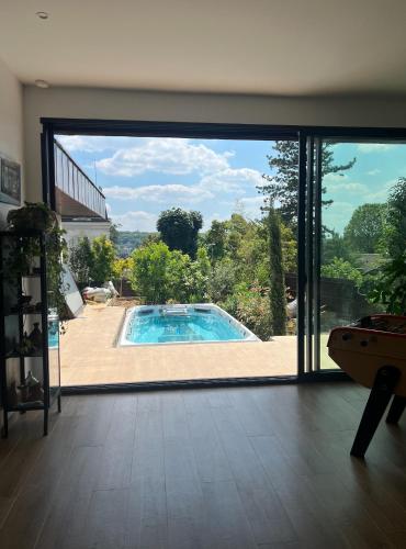 - une vue sur la piscine depuis une porte coulissante en verre dans l'établissement Magnifique Villa avec Jardin et Piscine proche Paris - Sèvres, à Sèvres
