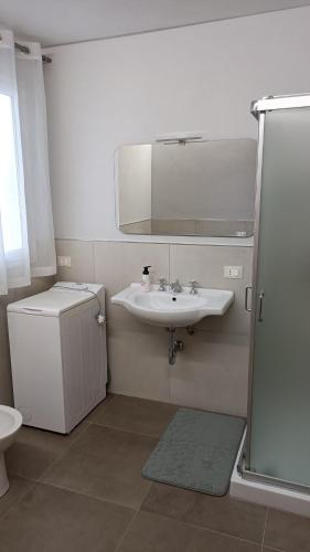 biała łazienka z umywalką i lustrem w obiekcie Santa Genoveffa Apartment w Trapani