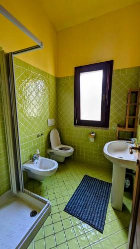 a green tiled bathroom with a sink and a toilet at Appartamento con Piscina - Luna Ruja Palau in Palau
