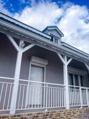 a house with a porch with a white railing at Ka Villa Location in Pointe-Noire