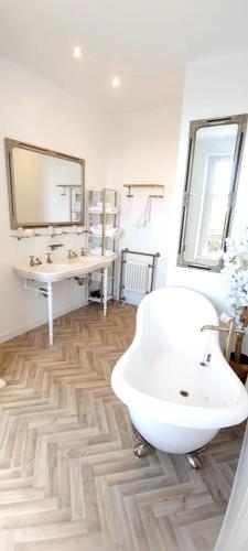 une salle de bain avec une baignoire blanche et un lavabo dans l'établissement Chambre Cocteau avec vue sur le Mont Saint Michel, à Champeaux