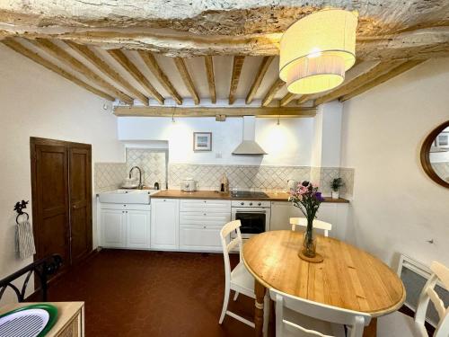 une cuisine avec une table en bois et des armoires blanches dans l'établissement Charming house in Valbonne village, à Valbonne