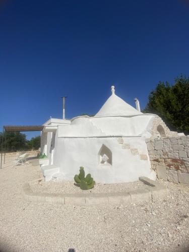 a white building with a cactus in front of it at Trullo Moi in Ostuni